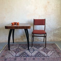 a table with two chairs sitting next to it on top of a rug in front of a wall