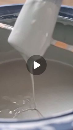 a person pouring milk into a blue bucket