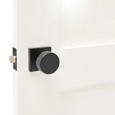 an open door with a black knob on the side and a white wall behind it