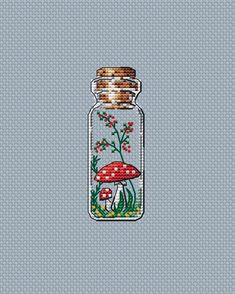 a glass jar filled with mushrooms on top of a blue surface next to a plant