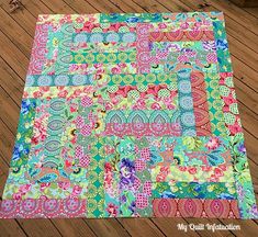 a multicolored patchwork quilt on a wooden floor