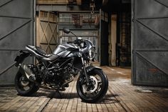 a black motorcycle parked in front of an open garage door on a brick floored area