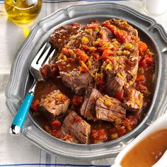 a silver plate topped with meat and vegetables next to a cup of tea on top of a table