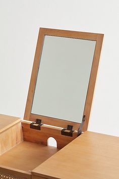 a mirror is sitting on top of a wooden desk with drawers underneath it and an open drawer below the mirror