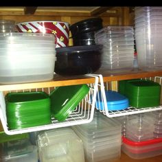 plastic containers are stacked up on shelves in a storage room, with lids and trays