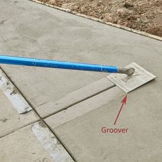 a blue umbrella laying on top of a cement floor next to a sidewalk with an arrow pointing towards the ground