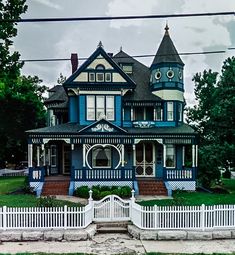 a large blue and white house sitting on top of a lush green field