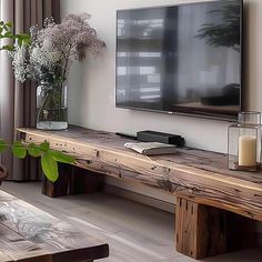 a flat screen tv sitting on top of a wooden table next to a vase filled with flowers