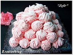 pink frosted cupcakes sitting on top of a black plate next to a rose