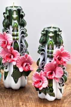 two vases with pink flowers are sitting on a table next to a planter