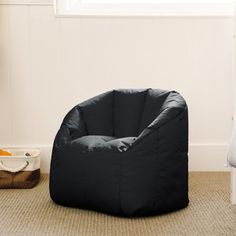 a black bean bag chair sitting on top of a carpeted floor next to a window