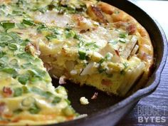 an omelet with green onions and other toppings in a black skillet