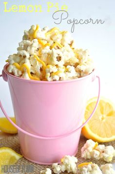 a pink bucket filled with popcorn sitting on top of a table next to sliced lemons