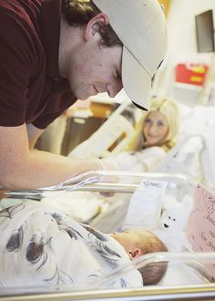 a man is looking at a baby in a hospital bed