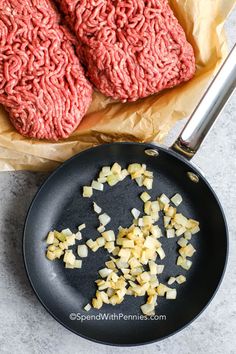 raw ground beef and onions cooking in a frying pan on a counter top next to a pair of meat patties