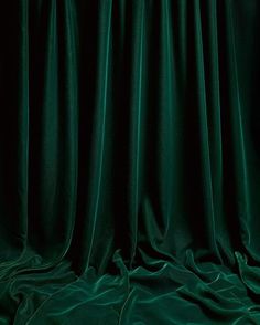 an image of a dark green curtain that is drapes open to reveal the light