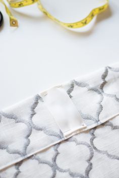 scissors, tape and measuring tape are laying on the table next to an empty piece of fabric