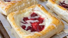 several pastries sitting on top of a baking pan covered in cheese and strawberries