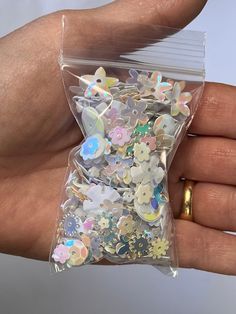 a person's hand holding a clear bag filled with lots of small stickers