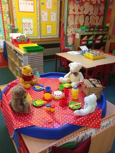 two teddy bears are sitting at a table with food and cups on it in a classroom