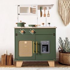 a green kitchen cabinet with utensils on the top and an oven above it