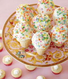 small cupcakes with sprinkles on a gold plate next to other cupcakes