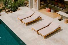 two lounge chairs sitting next to a swimming pool in the middle of a patio area