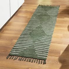 a green and white runner rug on the floor in a room with hardwood floors, cabinets and drawers