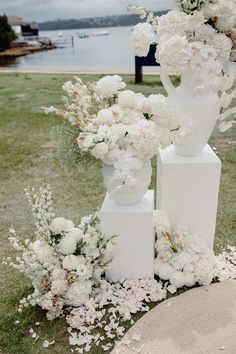 three white vases with flowers are sitting on the grass