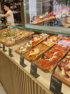 a display case filled with lots of different types of pizza on top of wooden trays