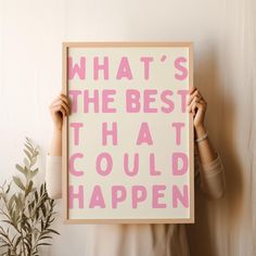 a woman holding up a pink and white poster with the words what's the best that could happen?