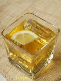 a square glass filled with ice and lemon