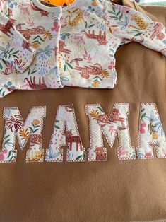 a baby's shirt with the word mama printed on it and an orange stuffed animal