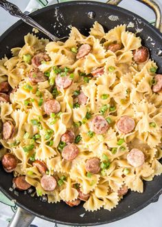 a skillet filled with pasta, sausage and peas