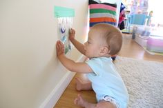 a baby is playing with some magnets on the wall