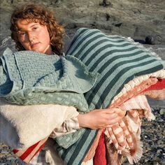 a woman wrapped in blankets on the beach