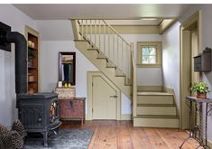 a living room filled with furniture and a fire place next to a stair case in front of a window