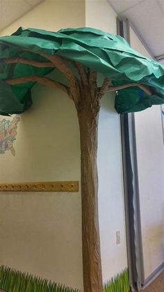 a paper tree is in the middle of an office cubicle decorated with grass and trees