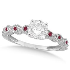 a white gold ring with red stones on the band and an oval cut diamond in the center