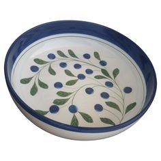 a blue and white bowl with green leaves on it