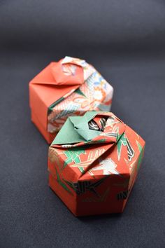 two origami boxes sitting side by side on a black surface with one folded up and the other closed