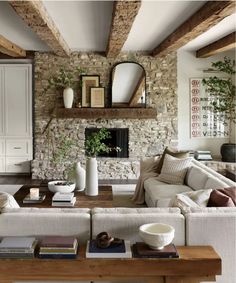 a living room filled with furniture and a fire place in the middle of a stone wall