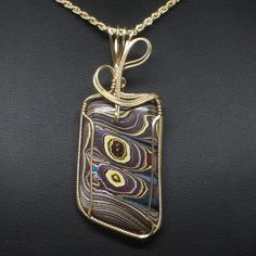 "Fordite Wire Wrapped Jewelry Description: *Designer Fordite Detroit Agate Cabochon: 40mm x 30mm Rectangle Shaped *Pendant Approximate Size: 2 3/4\" long including bail x 1 1/4\" at widest point *Free Rope Chain *Free Domestic Shipping - Arrives in Gift Box - Gift Wrapping Available The contemporary wire wrap jewelry is hand wire sculptured using 14k gold-filled wire around the recycled Fordite Detroit Agate cabochon to form this collector's item handmade wire wrap pendant statement necklace. Th Gold Agate Jewelry With Large Pendant, Gold Cabochon Agate Jewelry, Gold Agate Cabochon Jewelry, Yellow Gold Agate Jewelry Gift, Gold Agate Jewelry With Polished Finish, Yellow Gold Agate Jewelry For Gift, Fordite Jewelry, Wire Wrap Jewelry, Wire Wrap Pendant