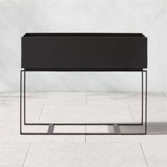 a black planter sitting on top of a white floor next to a metal frame