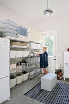 a woman standing in front of a shelf filled with lots of baskets and blankets on it's sides