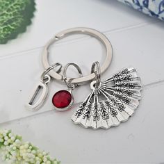 a silver key chain with a red glass charm hanging from it's center, on top of a white surface