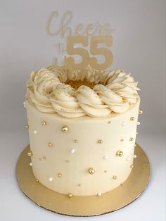 55th birthday cake with custom gold topper. Cream colored buttercream with piped ring on top, with gold sanding sugar, sprinkled with edible glitter and decorated with gold and pearl balls. 50th Bday Cake For Women Elegant, Gold Theme Birthday Cake, Cream Cake Design Birthday, Caramel Cake Design, Buttercream Cake Designs Birthday, Cheers To 60 Years Cake, Gold Cake Design Birthday, Gold Cake Birthday, Gold Themed Cake