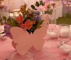 a pink butterfly shaped vase filled with flowers on top of a table