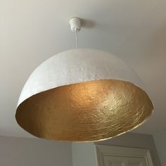 a white and gold light fixture hanging from the ceiling in a room with an open door