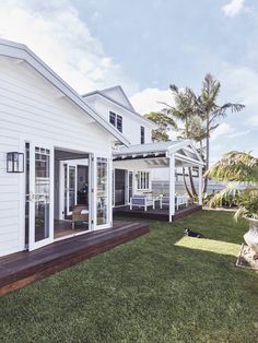 a white house sitting on top of a lush green field next to a wooden deck